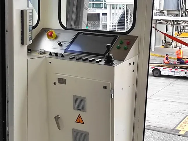 The same cab after modernization: new control desk with screen, joystick and safety signage