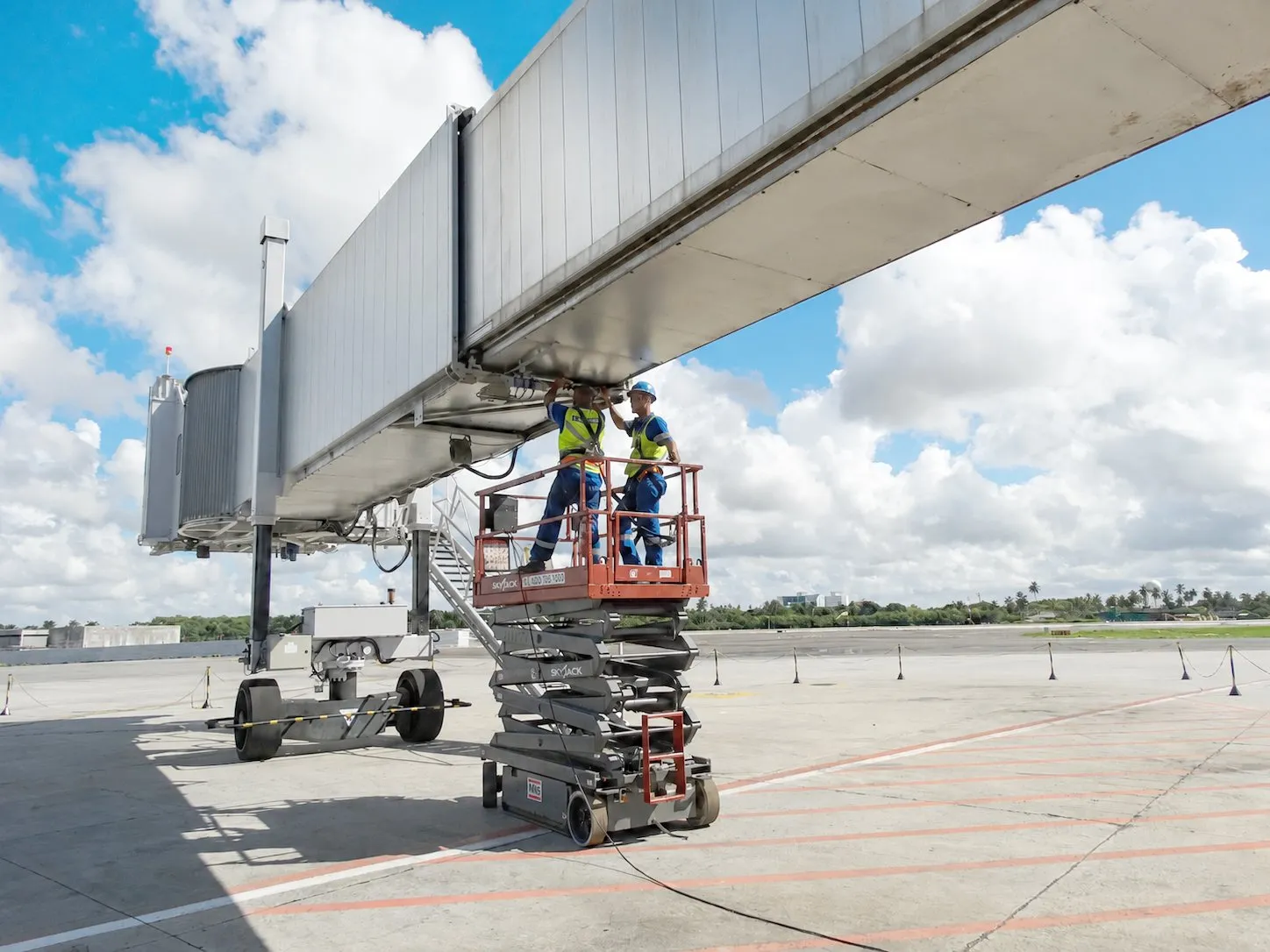 APS LATAM technical crew working from a scissor lift under a boarding bridge