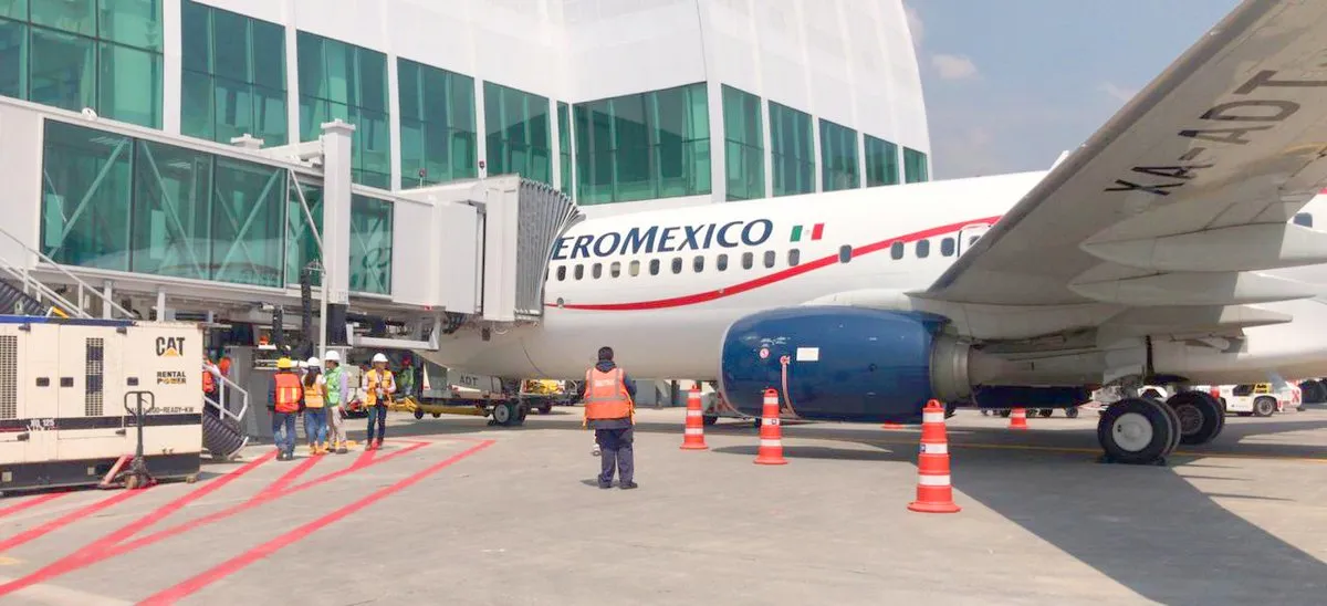 Passenger boarding bridge and an Aeroméxico aircraft on the apron of an airport in Mexico