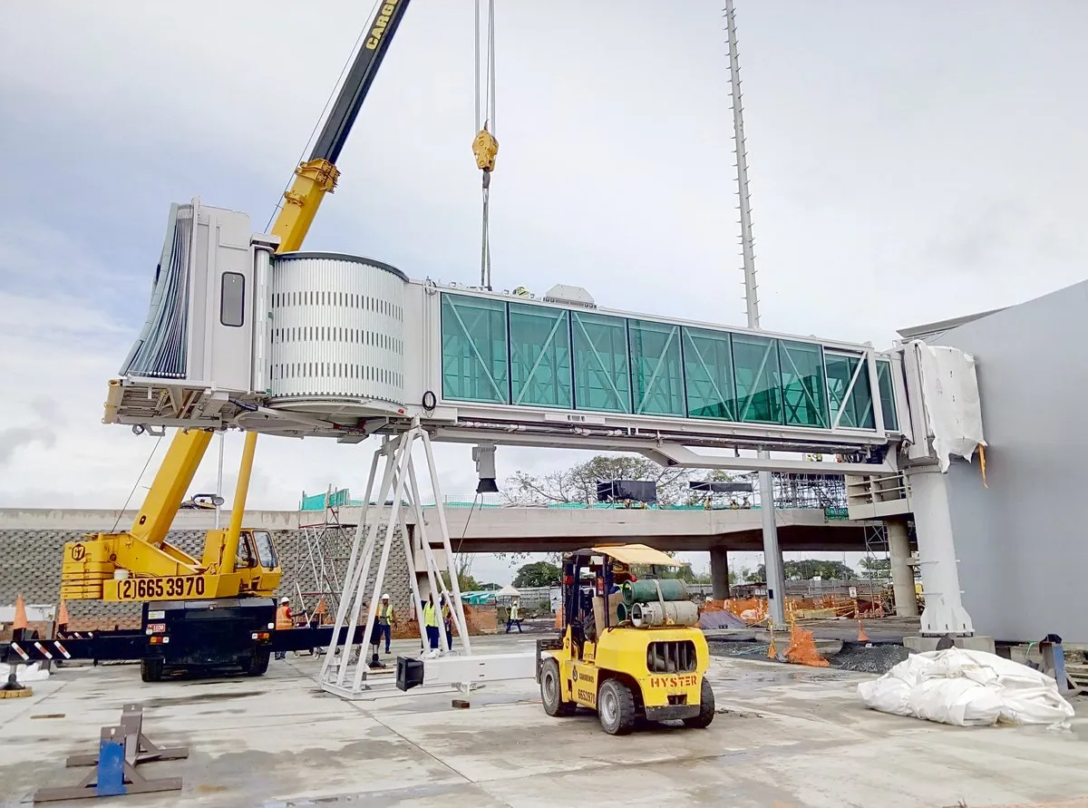 A new boarding bridge being assembled by crane at an airport in Colombia