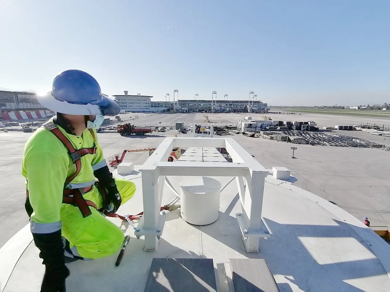 APS LATAM technician in a harness working on the roof of a boarding bridge